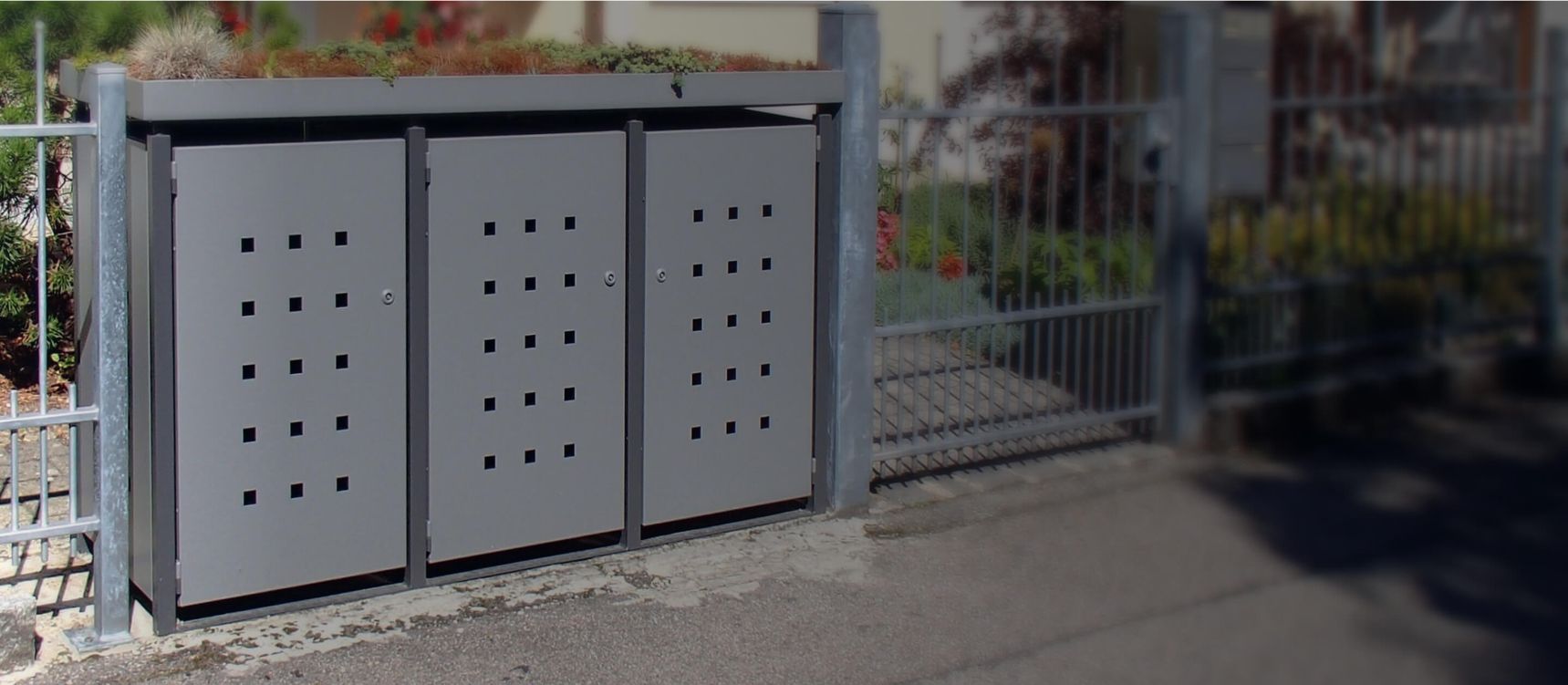 Müllboxen eingebaut in einen Zaun eines Vorgartens